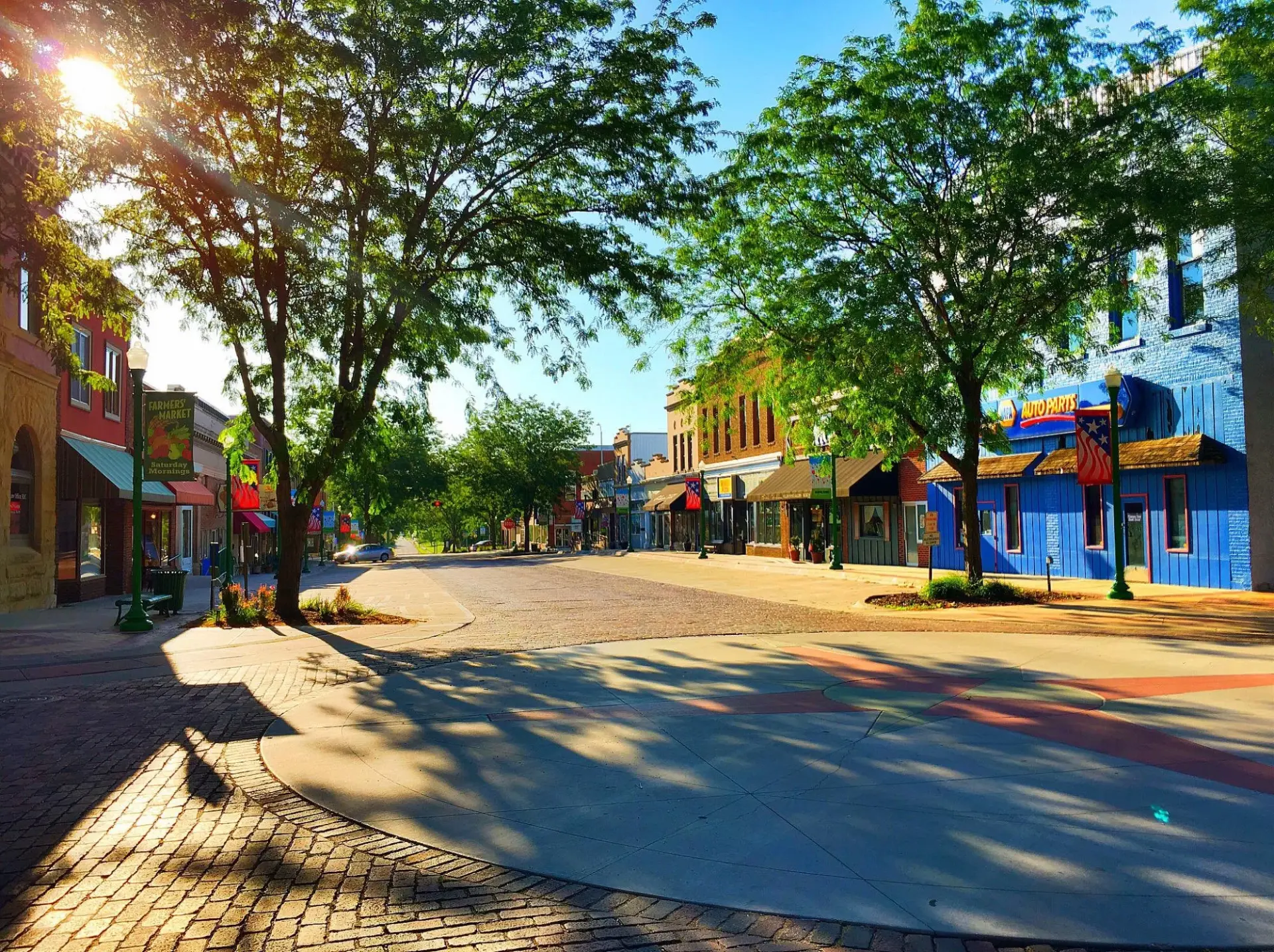 Sunny view of historic downtown Ashland, Nebraska with tree-lined brick streets and colorful storefronts